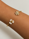 Pulsera Dúo Floral Encantado BRAVATA, detalle 3: pulsera rígida abierta con dos flores en los extremos; una flor con cinco pétalos rojos facetados y centro dora