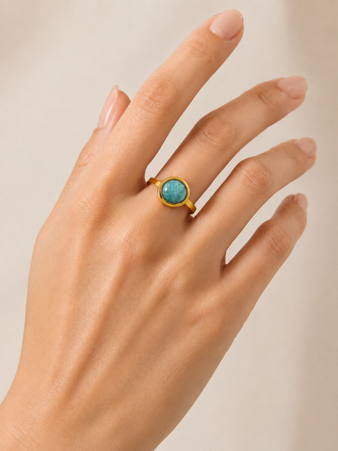 Modelo llevando el Anillo Arven dorado ajustable con piedra circular turquesa de BRAVATA.