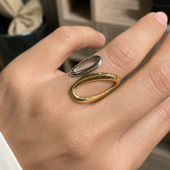 Anillo Aziel bicolor ajustable puesto en la mano, con diseño abierto y formas ovaladas en acabado dorado y plateado de BRAVATA.