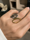 Anillo Aziel bicolor ajustable puesto en la mano, con diseño abierto y formas ovaladas en acabado dorado y plateado de BRAVATA.