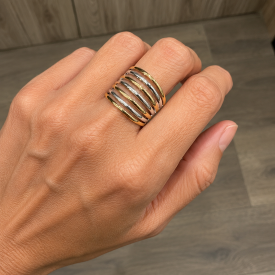 Modelo llevando un anillo ancho bicolor con bandas doradas y plateadas alternadas de BRAVATA.