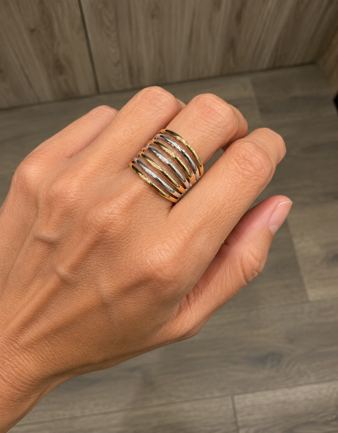 Modelo llevando un anillo ancho bicolor con bandas doradas y plateadas alternadas de BRAVATA.