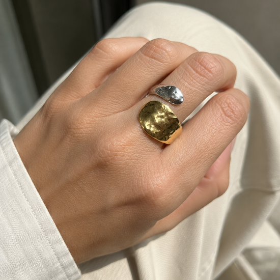 Anillo Nakoa bicolor ajustable puesto en la mano, con piezas martilladas en acabado dorado y plateado de BRAVATA.