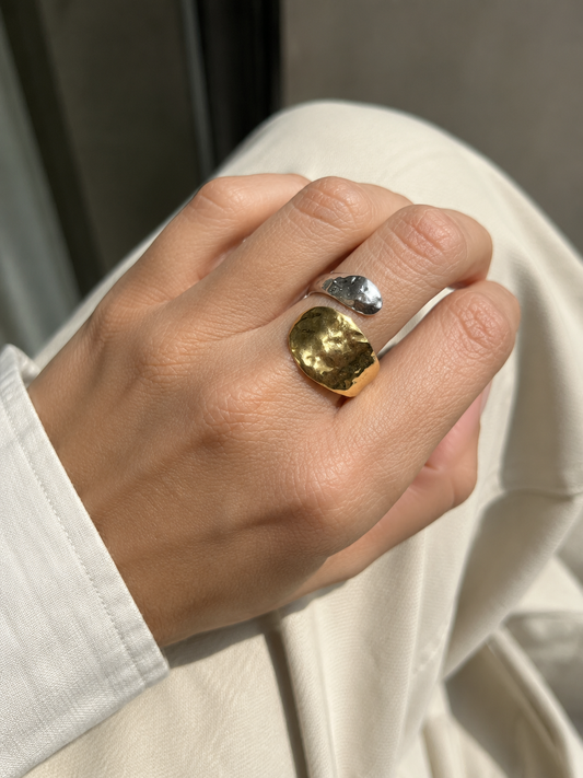 Anillo Nakoa bicolor ajustable puesto en la mano, con piezas martilladas en acabado dorado y plateado de BRAVATA.