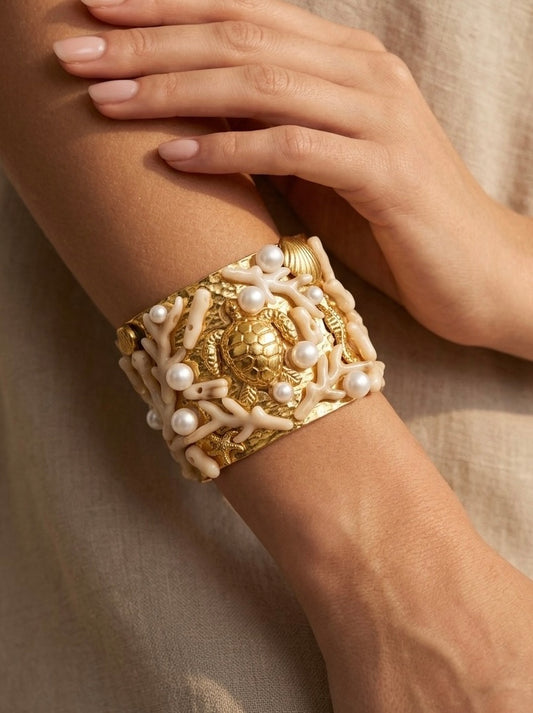 mujer llevando brazalete dorado ancho con tortuga coral blanco y perlas elegante
