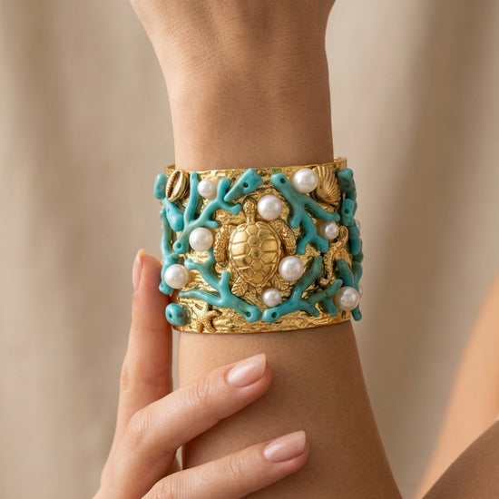 mujer llevando brazalete dorado ancho con tortuga coral turquesa y perlas estilo mediterráneo