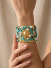 mujer llevando brazalete dorado ancho con tortuga coral turquesa y perlas estilo mediterráneo