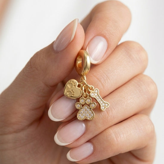 Mujer sujetando charm dorado con huella hueso y corazón joya de mascota Bravata