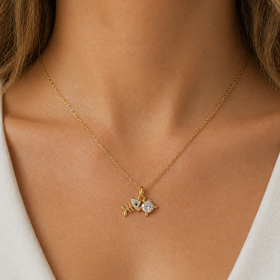 Detalle de colgante de pez dorado con circonita brillante en collar mujer Bravata