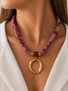Modelo llevando el Collar Amalfi rojo de pañuelo estampado con colgante ovalado dorado de BRAVATA.