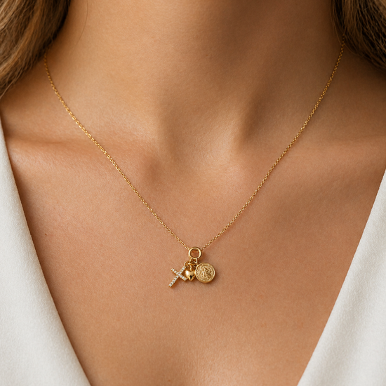 Mujer con collar amuleto dorado con cruz, corazón y moneda estilo elegante Bravata