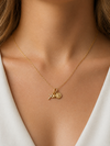 Mujer con collar amuleto dorado con cruz, corazón y moneda estilo elegante Bravata