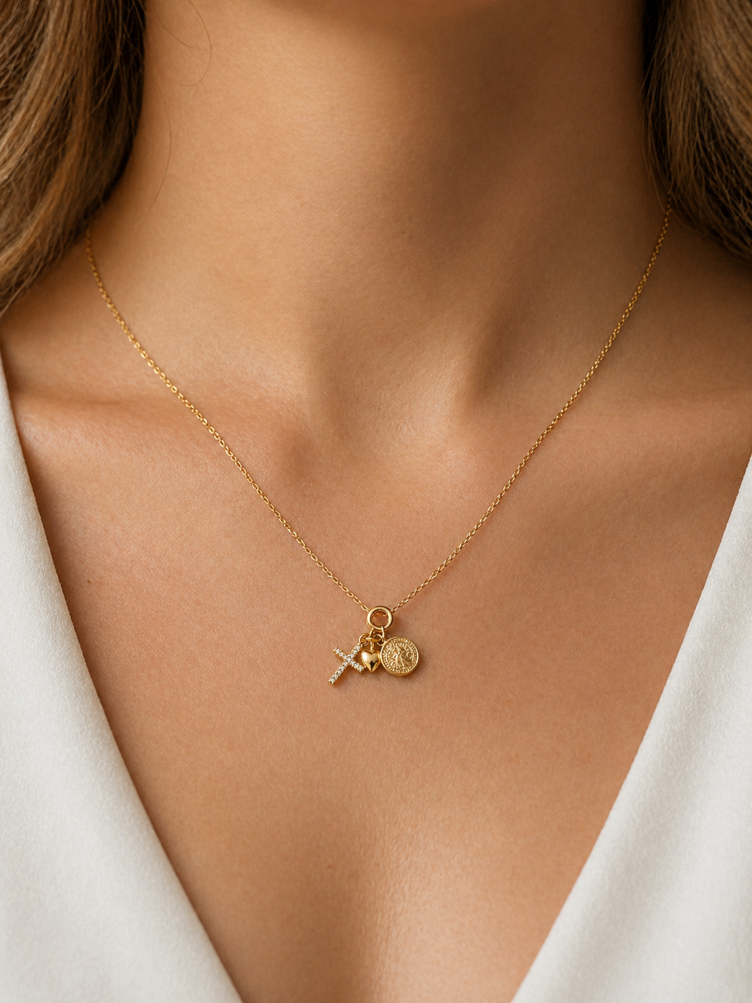 Mujer con collar amuleto dorado con cruz, corazón y moneda estilo elegante Bravata