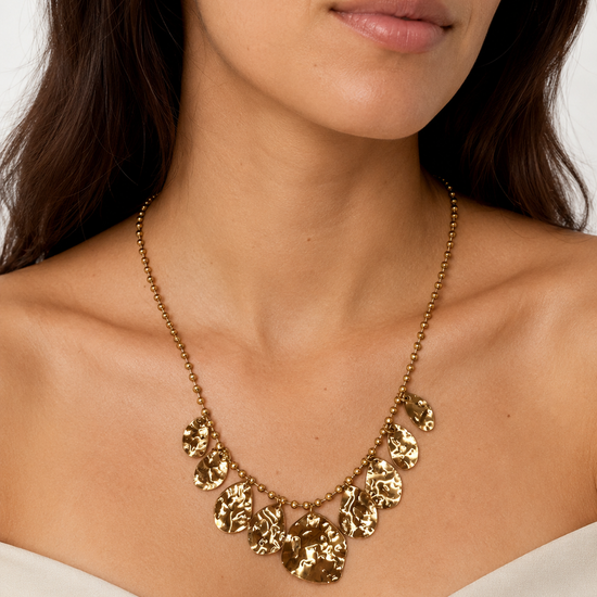 Modelo llevando el Collar Aurelia dorado con cadena de bolitas y placas colgantes de acabado martillado de BRAVATA.