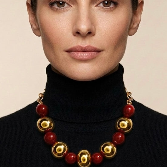 Mujer con collar de bolas doradas y rojas de estilo elegante