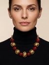 Mujer con collar de bolas doradas y rojas de estilo elegante