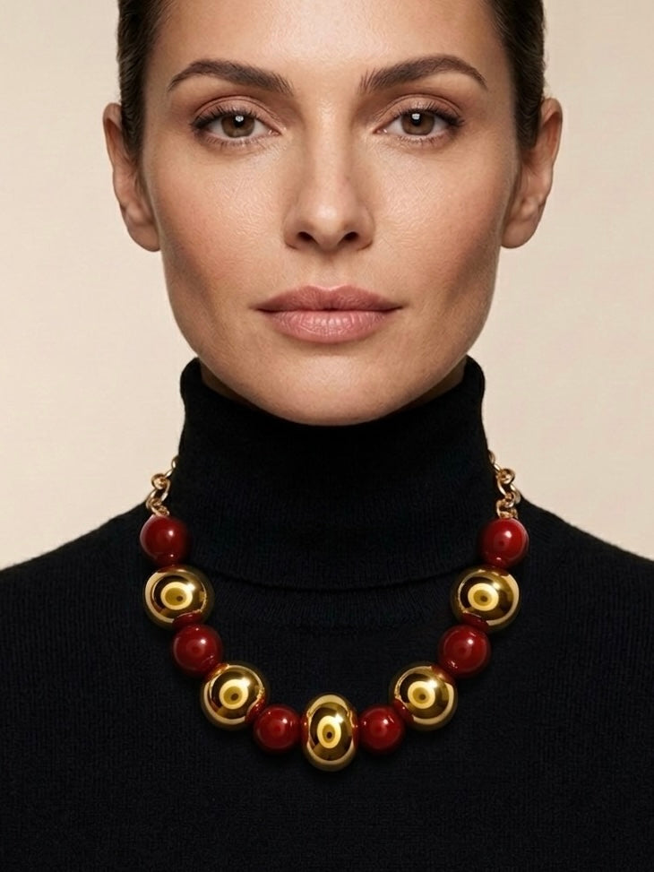 Mujer con collar de bolas doradas y rojas de estilo elegante