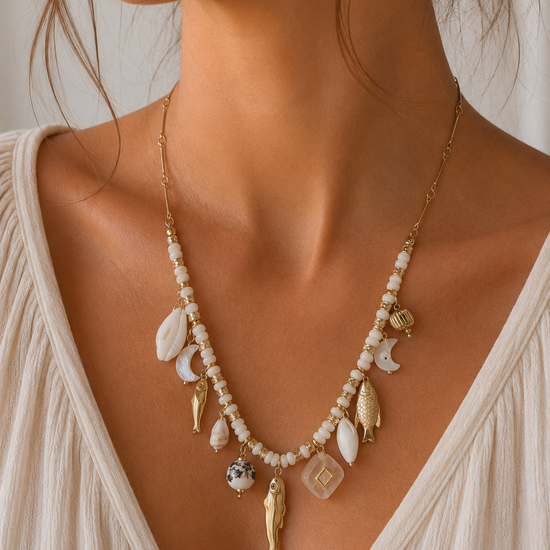 Mujer llevando collar dorado con abalorios blancos y charms inspirados en el mar de BRAVATA