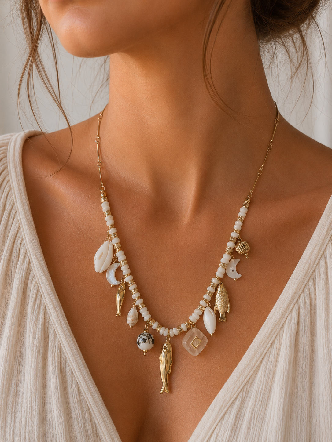 Mujer llevando collar dorado con abalorios blancos y charms inspirados en el mar de BRAVATA