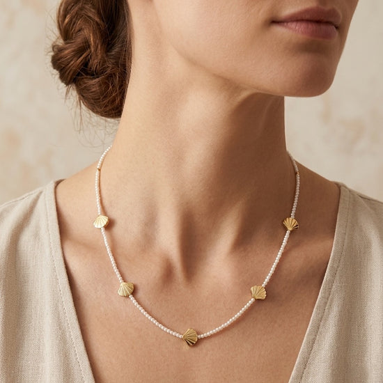Collar con perlas y conchas doradas puesto en mujer estilo elegante y veraniego Bravata