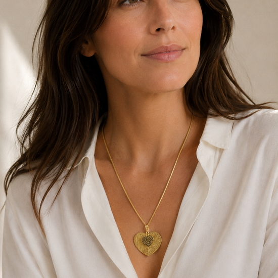 Mujer llevando collar dorado con colgante de hoja corazón de BRAVATA