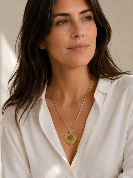 Mujer llevando collar dorado con colgante de hoja corazón de BRAVATA