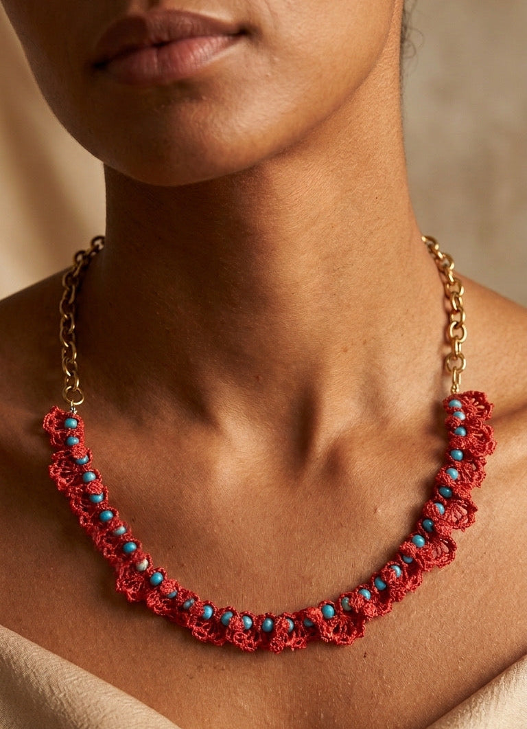 Collar artesanal de crochet en color coral con detalles de turquesas sobre modelo