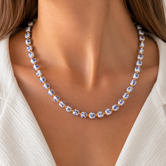 Modelo llevando el Collar Delfina con cuentas de cerámica blanca y azul y detalles dorados de BRAVATA.