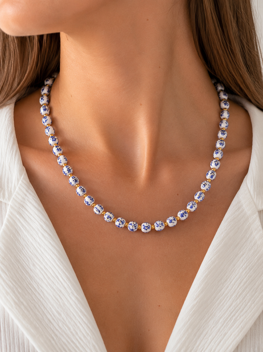 Modelo llevando el Collar Delfina con cuentas de cerámica blanca y azul y detalles dorados de BRAVATA.