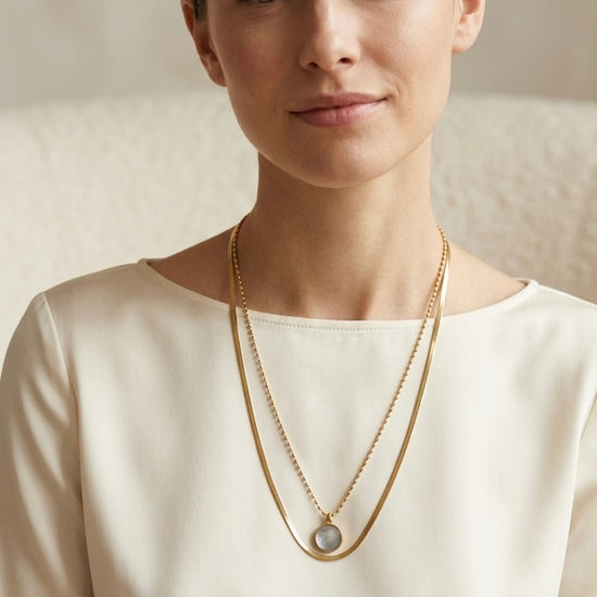 Mujer con collar dorado de doble cadena y cápsula de recuerdos Bravata