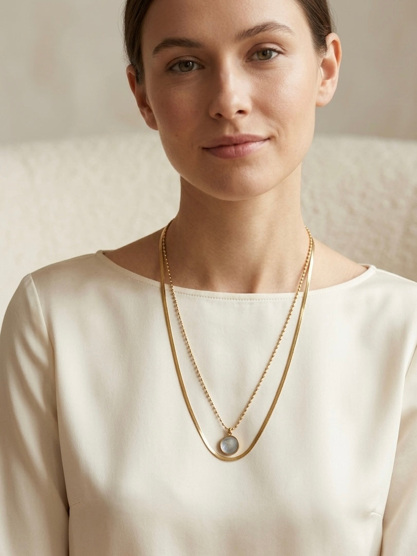 Mujer con collar dorado de doble cadena y cápsula de recuerdos Bravata