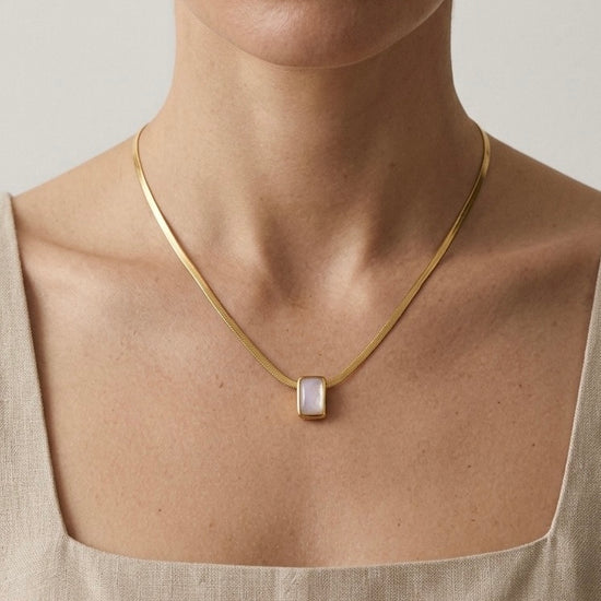 Mujer con collar dorado minimalista con piedra blanca rectangular