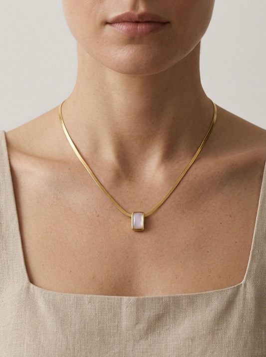 Mujer con collar dorado minimalista con piedra blanca rectangular