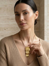 Mujer con collar dorado texturizado elegante Bravata