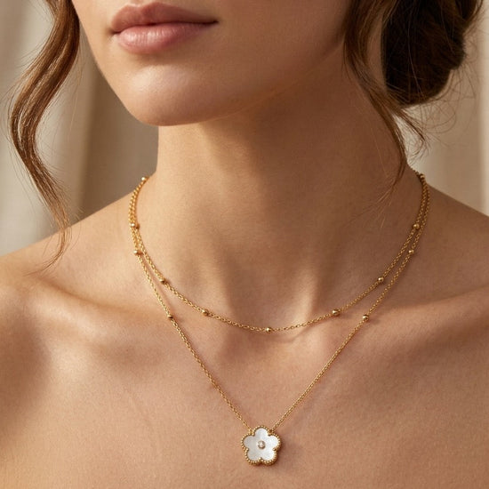 mujer con collar dorado doble cadena con colgante de flor blanca elegante