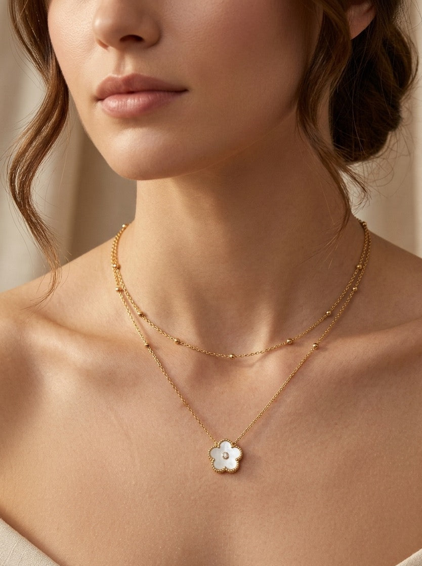 mujer con collar dorado doble cadena con colgante de flor blanca elegante