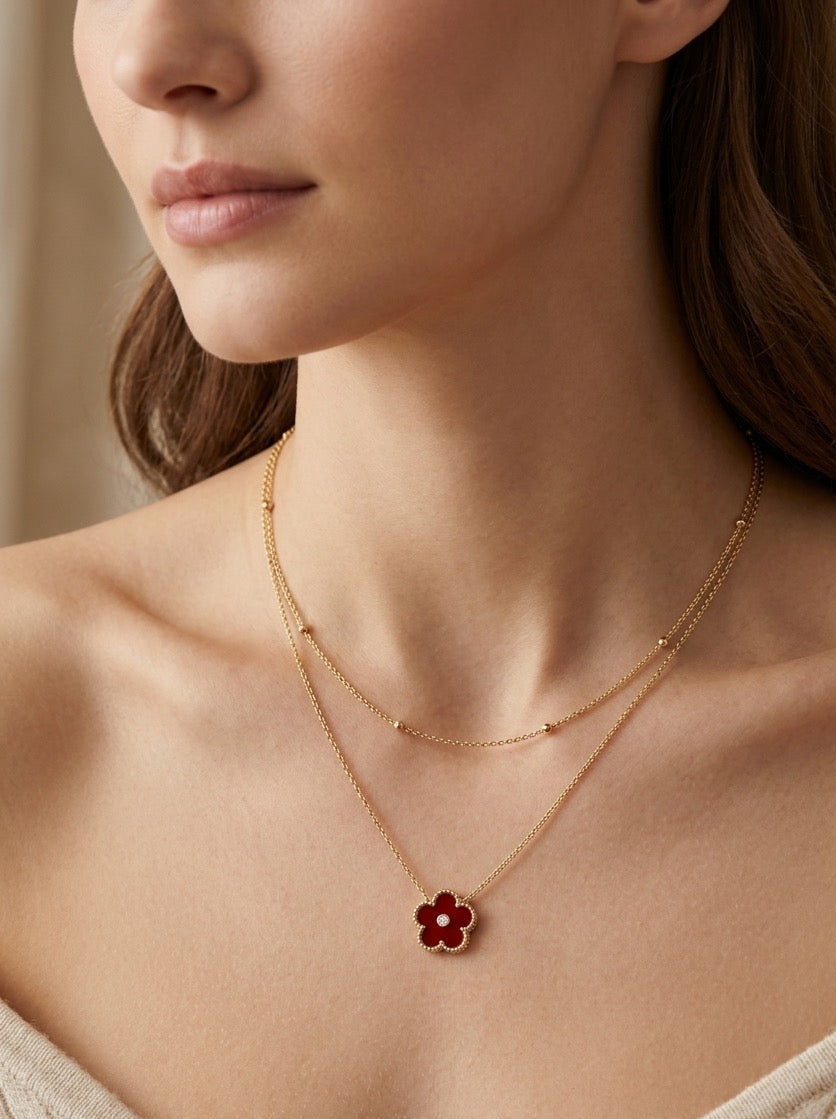 mujer con collar dorado doble cadena con colgante de flor roja elegante