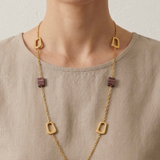 Mujer con collar largo dorado geométrico con piezas malva