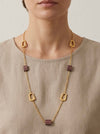 Mujer con collar largo dorado geométrico con piezas malva