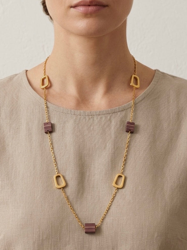 Mujer con collar largo dorado geométrico con piezas malva