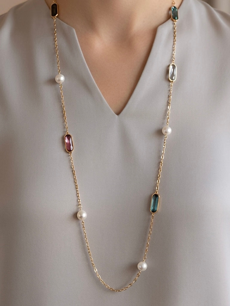 Mujer con collar largo dorado con piedras de colores y perlas Bravata