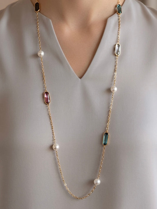 Mujer con collar largo dorado con piedras de colores y perlas Bravata