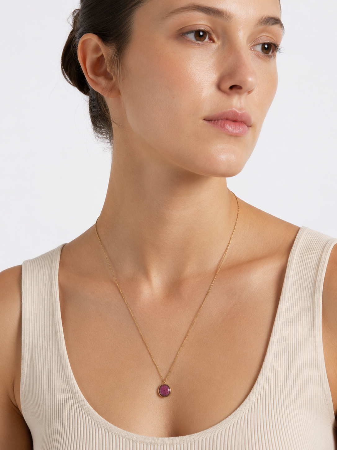 Modelo llevando el Collar Lúa dorado de cadena fina con colgante circular de piedra fucsia de BRAVATA.