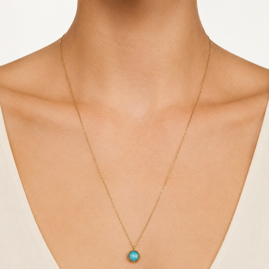 Modelo llevando el Collar Lúa dorado de cadena fina con colgante circular de piedra turquesa de BRAVATA.