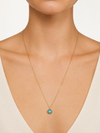 Modelo llevando el Collar Lúa dorado de cadena fina con colgante circular de piedra turquesa de BRAVATA.