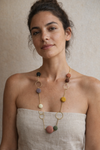 Mujer con collar minimalista de piedras naturales de colores y cadena dorada estilo elegante y natural