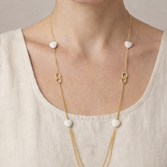 Mujer con collar largo dorado con corazones blancos estilo elegante