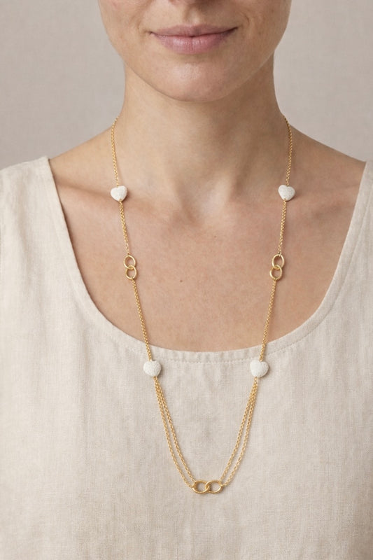 Mujer con collar largo dorado con corazones blancos estilo elegante