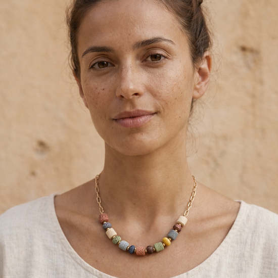 Mujer con collar de piedras volcánicas multicolor y cadena dorada estilo natural y elegante