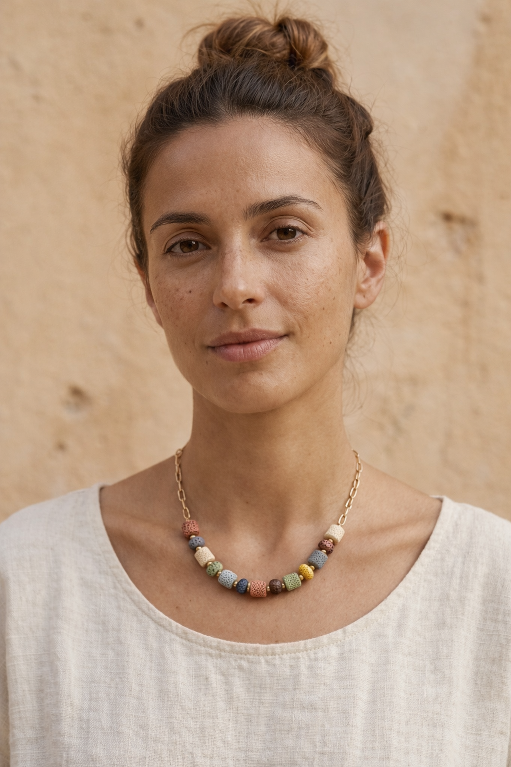 Mujer con collar de piedras volcánicas multicolor y cadena dorada estilo natural y elegante